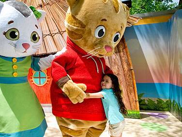 little girl hugging two storyland tiger mascots